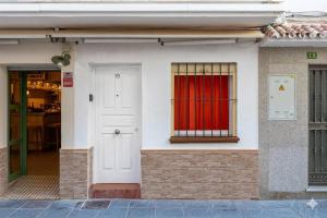 a white building with a red curtain in a window at Casa Marbella in Fuengirola