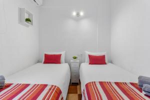 two beds in a room with white walls and red pillows at Casa Marbella in Fuengirola