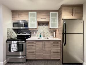 a kitchen with stainless steel appliances and wooden cabinets at Oceanfront Studio with Loft - amazing views! in Qualicum Beach