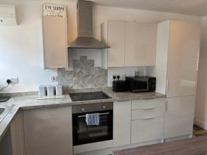 a kitchen with white cabinets and a stove top oven at Middlecroft in Chesterfield +6 photos