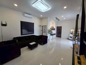 a living room with a black couch and a tv at 65 Poolvilla in Ban Tao Than