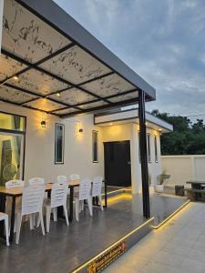 a patio with white chairs and a wooden table at 65 Poolvilla in Ban Tao Than