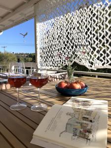 two glasses of wine sitting on a table with a book at Lemonaki House Lefkada in Asprogerakata
