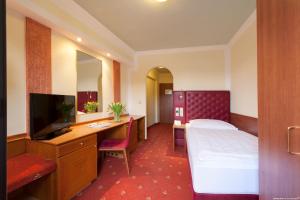 a hotel room with a bed and a desk and a tv at Hotel Weinberg GmbH in Regau