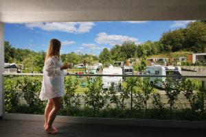 a woman standing on a balcony looking out at a marina at Mobile Homes Camping Plitvice in Smoljanac