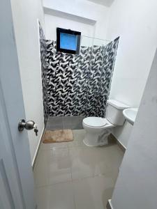 a bathroom with a toilet and a tv on a wall at Aparta Hotel Mi Dulce Amanecer 2 in Cabrera +17 photos