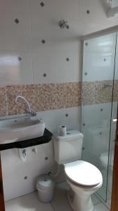 y baño con aseo, lavabo y ducha. en Pousada Iguape Apartamentos - Unidade Ilha Comprida, en Ilha Comprida