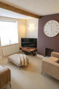 a living room with a large clock on the wall at Windsor Cottage in Holmfirth