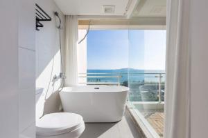 a bathroom with a tub and a toilet and a window at Yumian Cloud Seaview Hotel in Sanya +82 photos