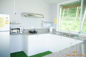 a kitchen with white cabinets and a sink and a window at Phuket Muay Thai House in Chalong 