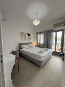 a white bedroom with a bed and a window at Akti Rooms And Studios in Livadi