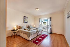 a bedroom with two beds and a door to a balcony at Casa Brisa Tavira in Tavira
