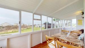 a dining room with a table and chairs and windows at F12 West View, Riviere Towans in Hayle