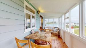 a dining room with a table and chairs and windows at F12 West View, Riviere Towans in Hayle