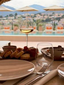 a table with a glass of wine and a plate of food at Maison Nova - Boutique Hôtel & Spa in Collioure