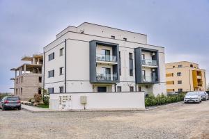 a white building with cars parked in a parking lot at Matcha Garden apartment in Dumbrăviţa