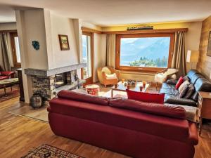 a living room with a red couch and a fireplace at Chalet Chalet Aglaia by Interhome in Crans-Montana