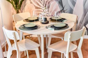 a white dining room table with four chairs and a white table and chairsuggest at Matcha Garden apartment in Dumbrăviţa