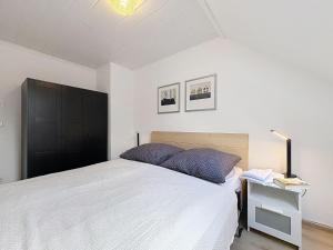 a bedroom with a white bed and a black cabinet at Apartment Am Sternberg 224 by Interhome in Frankenau