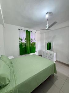 a bedroom with a green bed and green curtains at Aparta Hotel Mi Dulce Amanecer 2 in Cabrera