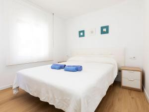 a white bedroom with two blue pillows on a bed at Apartment Blue Ocean-3 by Interhome in Llança