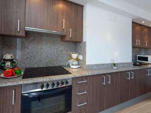 a kitchen with wooden cabinets and a stove top oven at Apartment Blue Ocean-3 by Interhome in Llança +13 photos