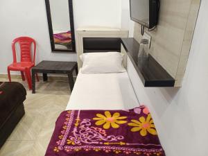 a small room with a bed and a red chair at Hotel Sanwariya Palace in Haridwār