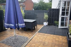 a blue umbrella on a patio with a table at Piets Monteurwohnung Sandstedt in Hagen im Bremischen