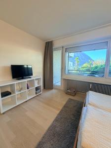 a living room with a tv and a large window at Holiday on The Lake Lugano 2 in Bissone