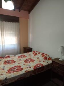a bedroom with a bed with a floral bedspread at Duplex a pazos del muelle in Mar de Ajó +2 photos
