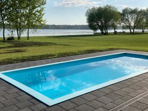 a swimming pool in a yard with a field and a lake at Idille2 in Ikšķile
