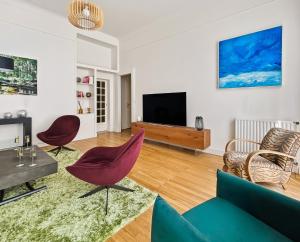 a living room with a flat screen tv and chairs at Osez Nantes cœur de ville! T3 chic et spacieux in Nantes