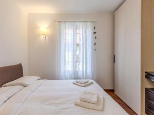a bedroom with a white bed and a window at Apartment di Lalla by Interhome in Lierna