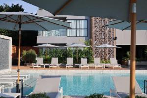a pool with chairs and umbrellas next to a building at TARA Bangkok Riverside Formerly GLOW Bangkok Riverside in Bangkok