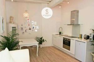a white kitchen with a table and a stove at Côté Chapelle Arles Centre in Arles