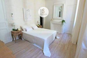 a white bedroom with a bed and a fireplace at Côté Chapelle Arles Centre in Arles