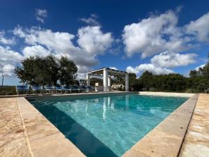 a pool with a gazebo and blue sky at Trullo Acquario in Castellana Grotte