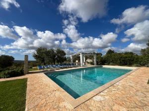 a swimming pool with chairs and a gazebo at Trullo Acquario in Castellana Grotte