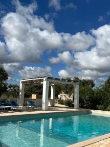 a pool with a gazebo and chairs next to it at Trullo Acquario in Castellana Grotte
