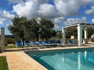 a swimming pool with chairs and a gazebo at Trullo Acquario in Castellana Grotte