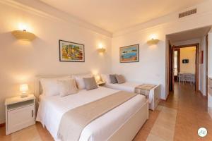 a white bedroom with two beds and a table at Luce di Mare, Vista Mare Sea View in Is Molas 