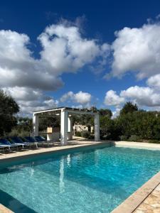 a swimming pool with chairs and a gazebo at Trullo Acquario in Castellana Grotte +60 photos