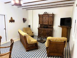 a living room with a tv and a couch and chairs at Hotel A Posada in Tembleque