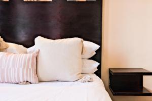 a bed with white pillows and a black headboard at Isiphephelo Property in Johannesburg