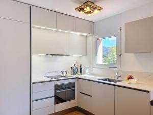 a kitchen with white cabinets and a sink and a window at Apartment Caslago by Interhome in Caslano