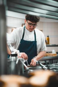a man in a kitchen preparing food in a kitchen at Logis Hôtel & Restaurant Le Cheval Blanc et Clovis in Vouillé +44 photos