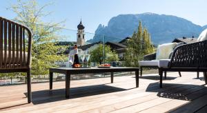a patio with two chairs and a table on a deck at LeFie in Vols am Schlern