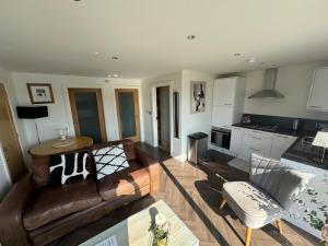 a living room with a leather couch and a kitchen at Lakeside Apartment in Enniskillen +10 photos