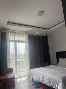 a bedroom with a bed and a large window at Kigali Legacy Villa Homes in Kigali