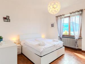 a white bedroom with a large bed and a chandelier at Apartment Onda Blu by Interhome in Gera Lario